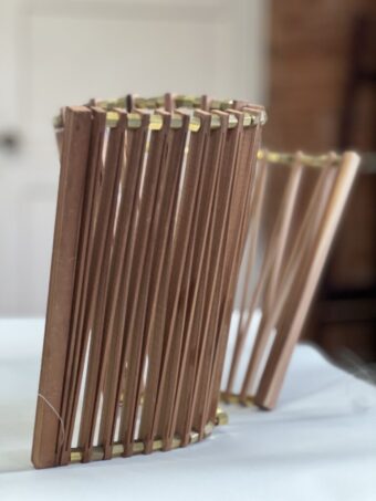 Articulated Form Standing wood sculpture with vertical slotted segments connected in a curved form by brass pieces, shown upright on a white surface.