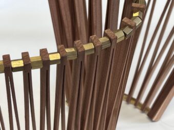 Articulated Form Close-up of upright wooden slats linked by brass elements in a curved sculptural form, showing the balance between structure and flexibility.